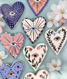 five heart shaped plates with different designs on them and flowers in the middle one has an eye painted on it