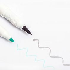 two pens sitting next to each other on top of a white paper with blue and green writing