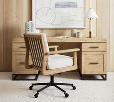 an office chair sits in front of a desk with a large painting on the wall