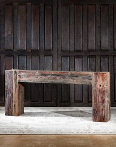 a wooden bench sitting in front of a wood paneled wall with two legs on each side