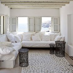 a living room filled with white furniture and lots of windows