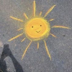 a yellow smiley face drawn on the pavement with chalk pastel and crayons