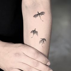 a woman's arm with three small tattoos on it, including two flying bats