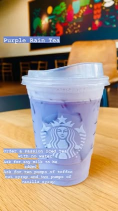 a purple starbucks cup sitting on top of a wooden table