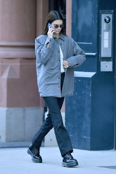 a woman walking down the street while talking on her cell phone