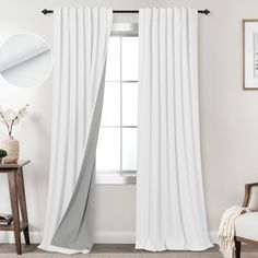 a white curtain hanging on the side of a window next to a chair and table