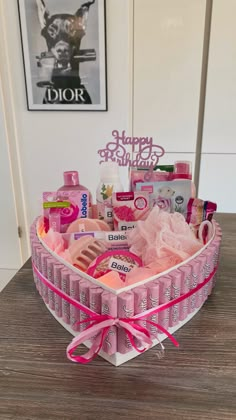 a pink heart shaped basket filled with lots of personal care items on top of a wooden table