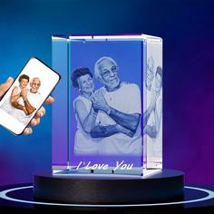 a person holding up a cell phone next to a glass block with an image of two people on it