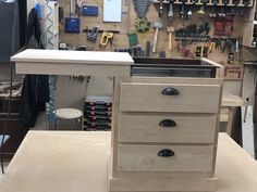 a workbench with drawers and tools hanging on it's wall in a workshop