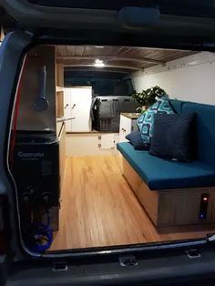 the interior of an rv with wood flooring and blue couch in the back door