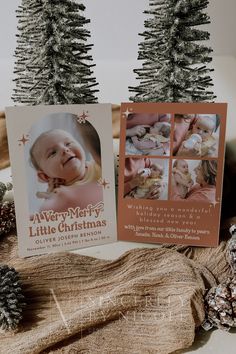 two christmas cards sitting on top of a table next to pine cones and fir trees