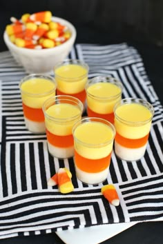 several glasses filled with orange and white jello on top of a striped table cloth