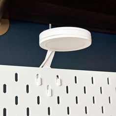 a close up of a white light fixture on a blue wall with holes in it