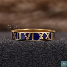 a gold and blue ring with roman numerals on the inside, sitting on a black surface