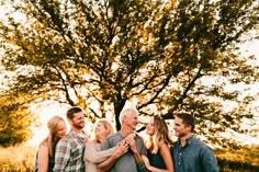 a group of people standing in front of a tree with their arms around each other