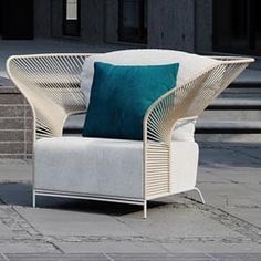 a white chair sitting on top of a stone floor next to a green pillow and some steps