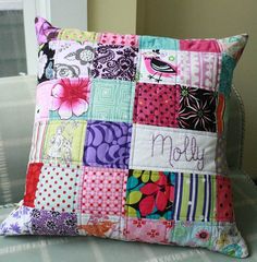 a colorful patchwork pillow sitting on top of a bed with the word mom written in cursive writing