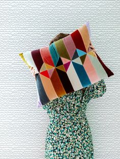 a woman holding a colorful pillow in front of her face