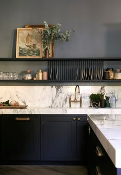 a kitchen with black cabinets and marble counter tops, gold faucets and brass pulls