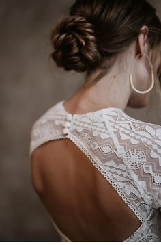 a woman in a white dress is looking down at her cell phone and wearing large hoop earrings