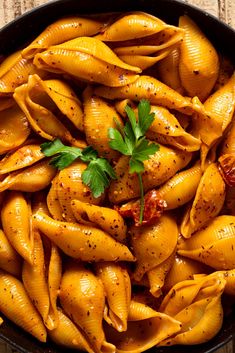 a skillet filled with pasta shells and garnished with parsley