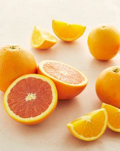 oranges and grapefruits cut in half on a white surface with one sliced open