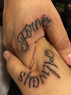 two hands with the words forever and mom tattooed on their palms, both holding each other's fingers