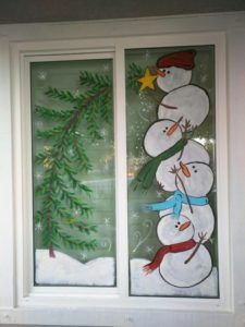 two frosted glass windows with snowmen and evergreens on them, one is green