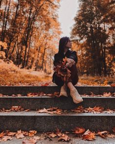 a woman sitting on some steps in the fall