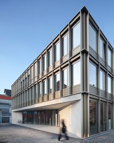 a person walking past a building that has many windows on the front and side of it