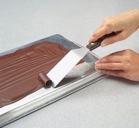 a person cutting into a chocolate cake with a knife