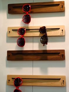 three pairs of sunglasses are hanging on the wall next to some wooden pegs and hooks