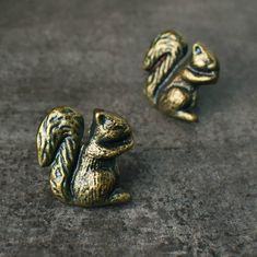 two small gold squirrel figurines sitting on top of a cement floor next to each other