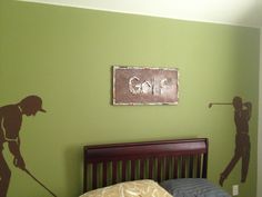 a bedroom decorated in green and brown with silhouettes of golf players on the wall