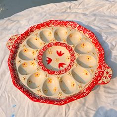 a red and white tray with eggs in it sitting on a tablecloth covered surface