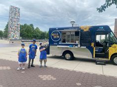 three people are standing in front of a food truck that is parked on the sidewalk