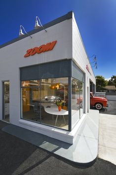 a store front with a table and chairs in the window next to a red truck