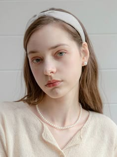 a young woman wearing a headband and pearls