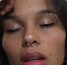 a close up of a person with a nose piercing on their nose and one eye closed