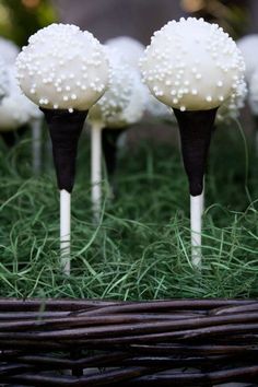 there are some cake pops with white frosting on them sitting in the green grass