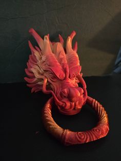 a close up of a red dragon head on a black surface with a light behind it