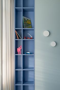 a blue book shelf with books and toys on it