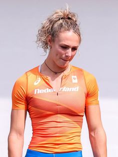 a woman wearing an orange shirt and blue shorts