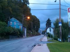 an empty street at dusk with no cars or people on the road and houses in the background