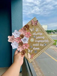 someone holding up a graduation cap with flowers on it