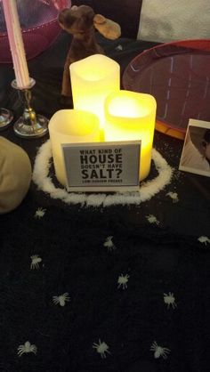 some candles and pictures on a table with a stuffed animal in the background at a house sale