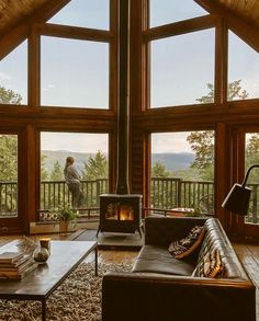 a living room filled with furniture and a fire place in front of two large windows