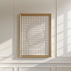 a white and gold frame hanging on the wall above a fireplace with a checkered pattern