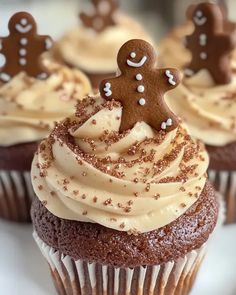 cupcakes with frosting and gingerbread decorations on top are sitting on a plate