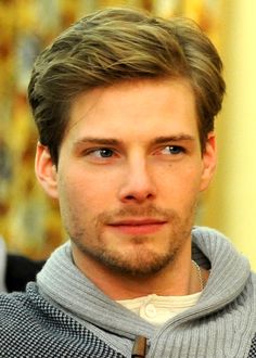 a close up of a person wearing a sweater and looking at the camera with a serious look on his face